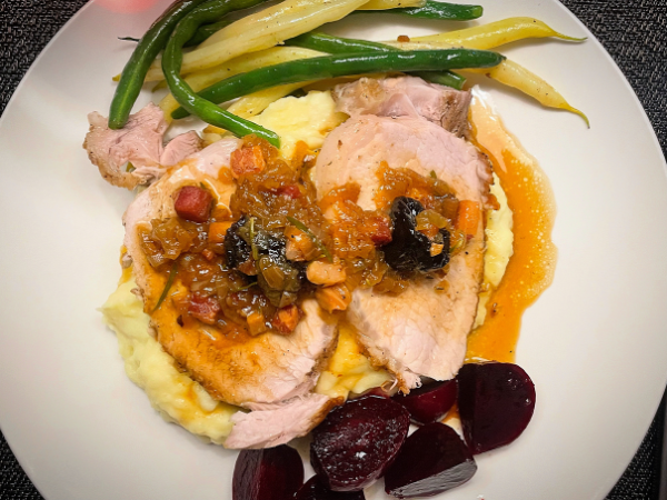 overhead view of sliced pork with prune sauce on a white plate